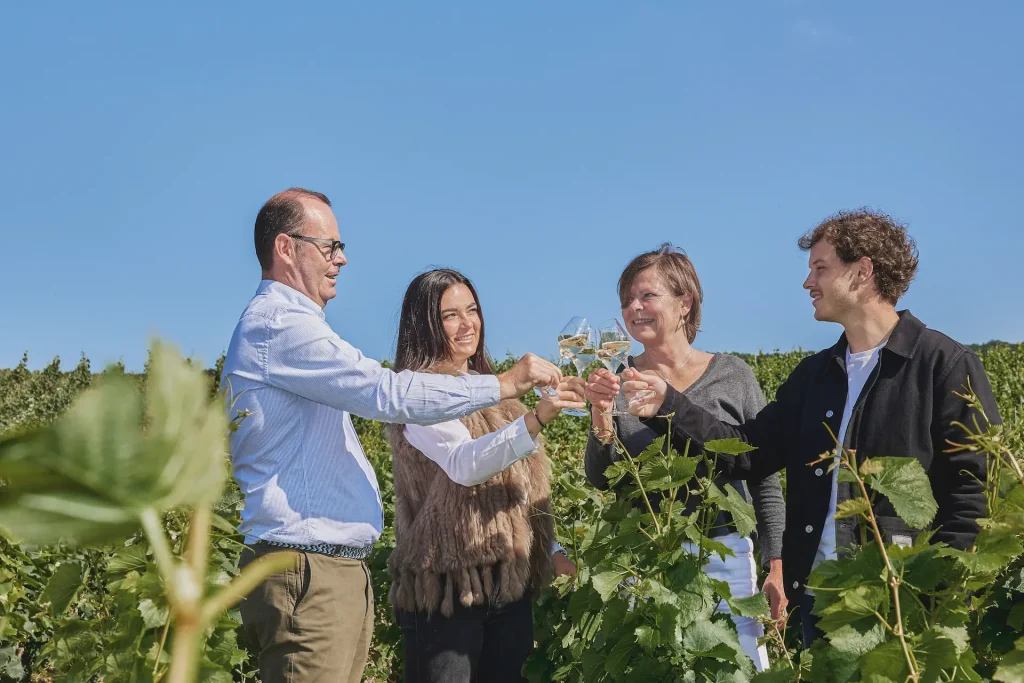 La famille Vollereaux trinque avec une coupe de champagne au milieu des vignes
