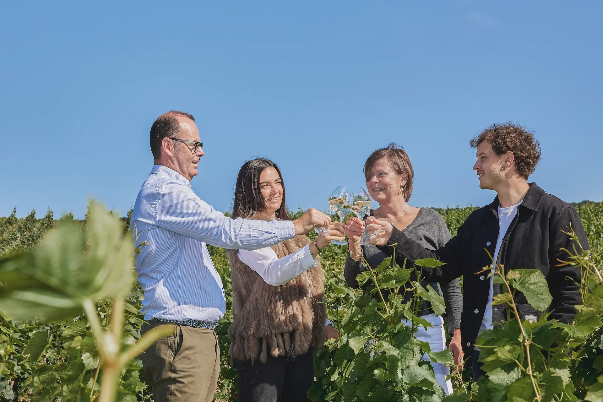 La famille Vollereaux trinque avec une coupe de champagne au milieu des vignes
